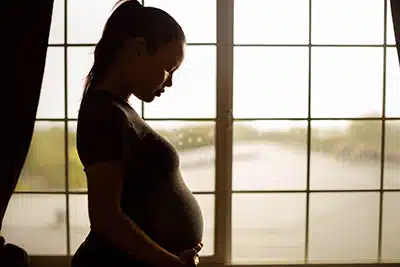 pregnant woman looking at her belly and thinking about adoption