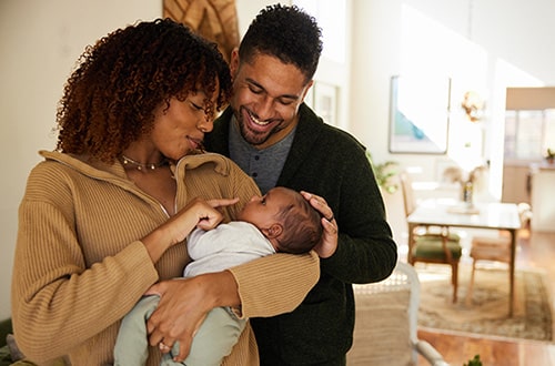 Loving adoptive mother and father holding their baby boy and celebrating adoption month